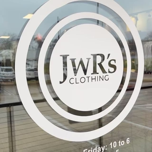 Brown leather key ring with brass metal loops and rivets on wood table.